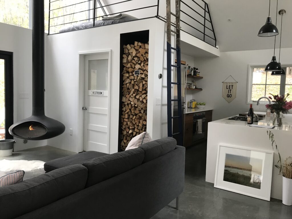 Interno casa con camino divano e soppalco. Fonte: Airbnb